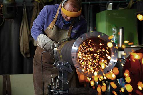 An employee welding a heat exchanger